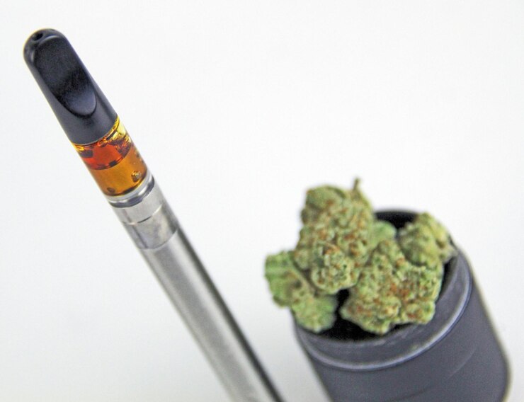 Photo a black and orange pencil with a stick of green and orange paint