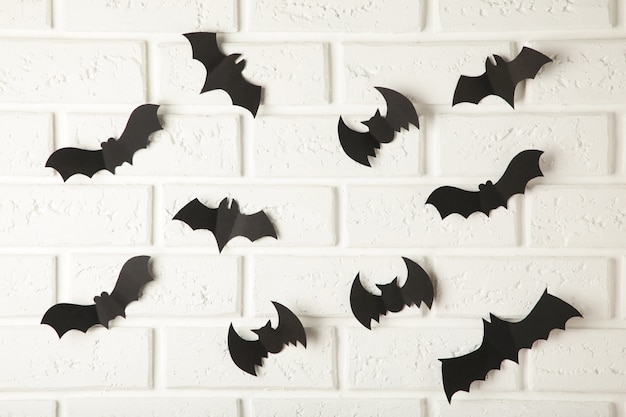 Black paper bats flying over white wall