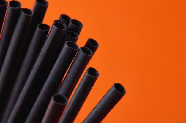 Black paper straws on orange background halloween party