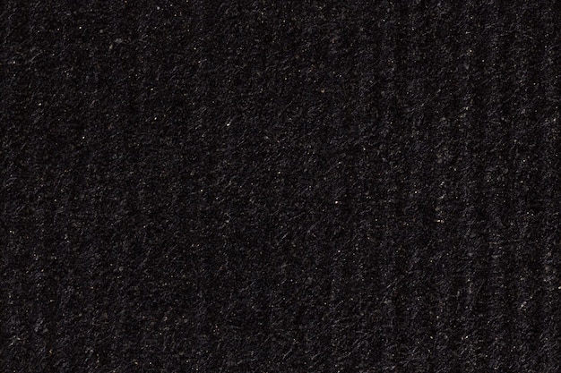 Black paper texture background with vertical stripes. High resolution photo.