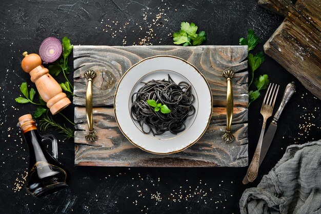 Black pasta on a plate Top view On a black background Free copy space