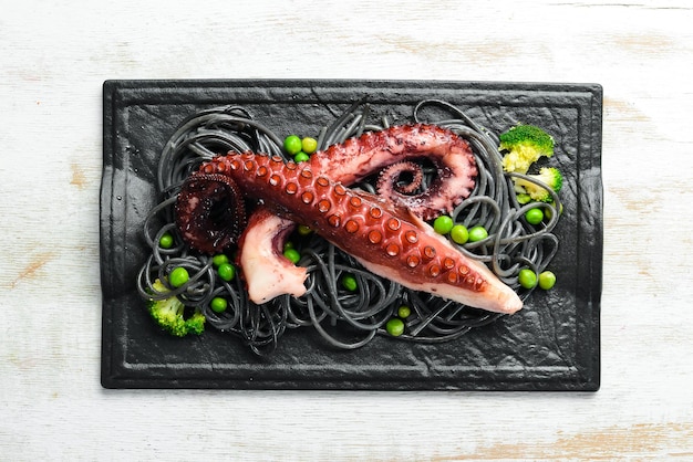 Black pasta with octopus tentacles on a black stone plate Seafood Top view Free space for your text