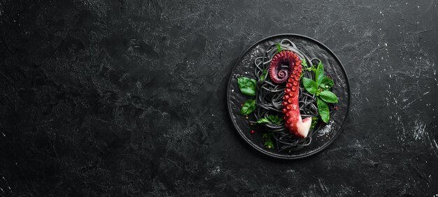 Black pasta with octopus tentacles. Seafood on a stone plate. In the old background. Top view. Free copy space.