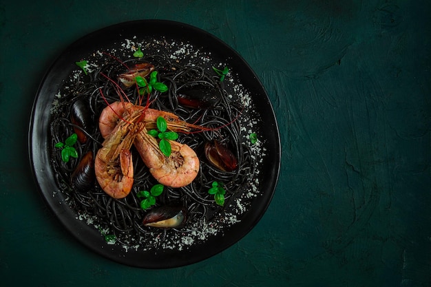 Черная паста с морепродуктами спагетти с креветками и мидиями вид сверху домашняя без людей