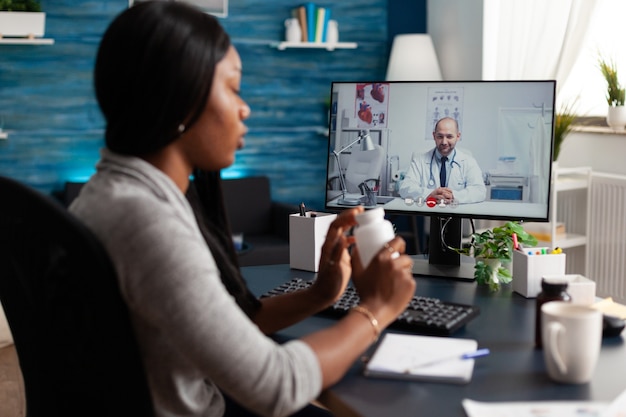 Black patient discussing pills treatment with physician doctor during online videocall meeting