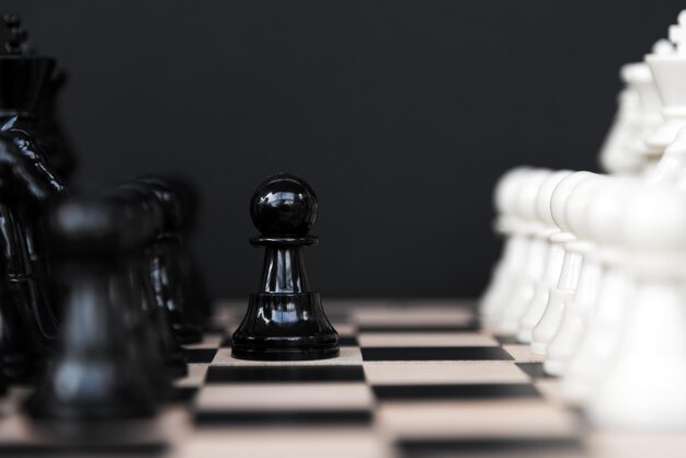 Black pawn against the White Chess Set on Black Background