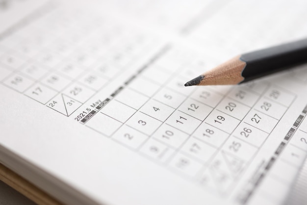 Black pencil lies on calendar with dates