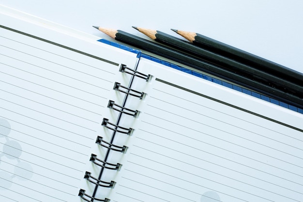 black pencil and notebook on white background,Top view of two kraft spiral notebook and black pencil