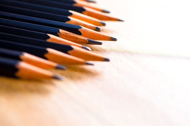 Black pencils isolated on wood surface background.Close up.