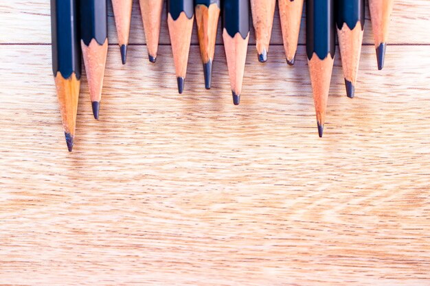 Black pencils isolated on wood surface background.Close up.