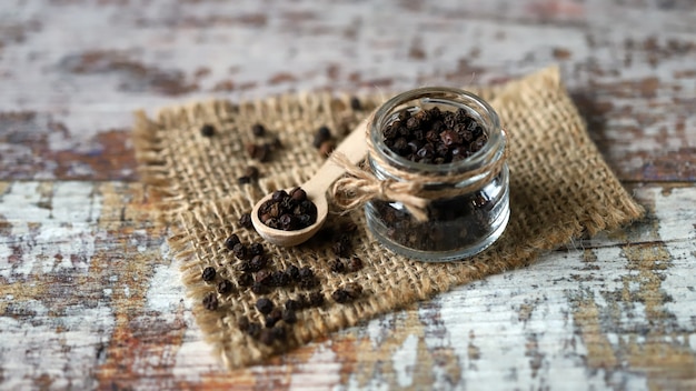 Black pepper in a jar and in a wooden spoon