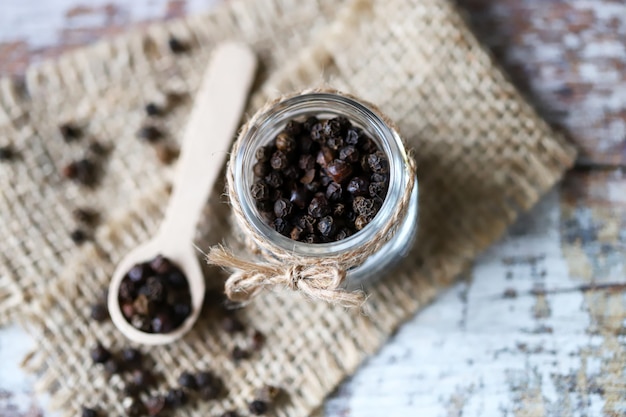 Black pepper peas. Black pepper in a jar and in a wooden spoon.