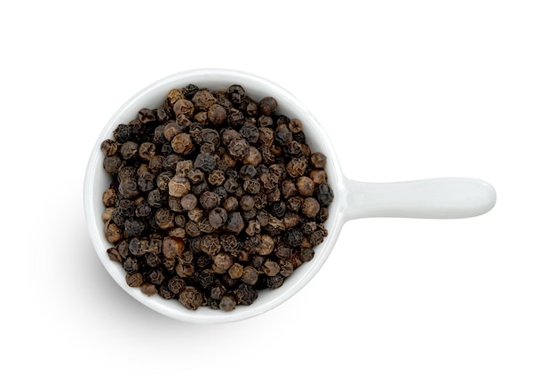 Фото Куча черного перца или семена черного перца в керамической чаше, изолированные на белом фоне