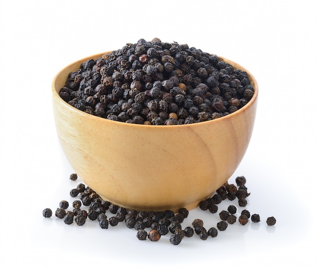 Black pepper in wood bowl on white 