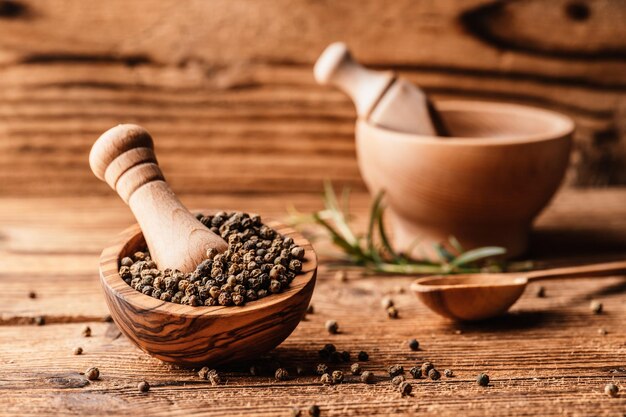 Black pepper in wood bowl on wooden table Spices on desk Organic spice dry peppercorn