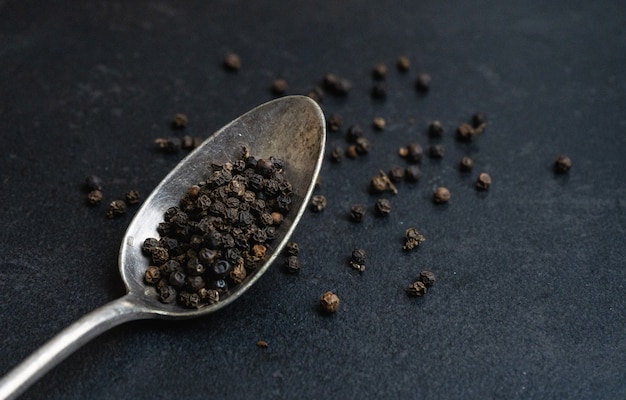 Black peppercorns in a silver spoon