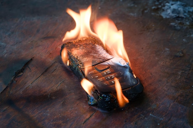 A black phone lies on the table and burns with a bright flame