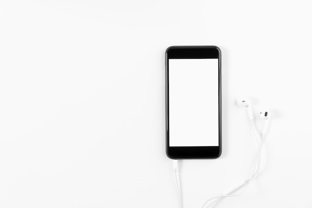 Black phone and white headphones on a white background