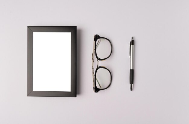 Photo black photo frame glasses and pen on white background