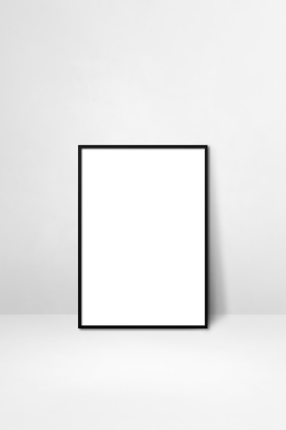 Black picture frame leaning on a white wall. Blank mockup template