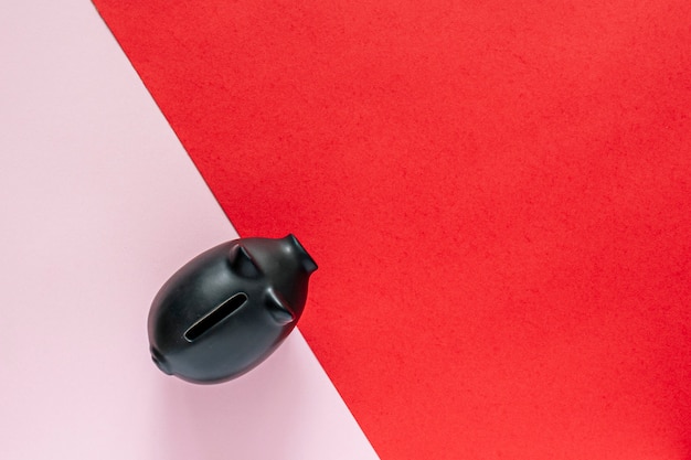 Black piggy bank over a pink and red table. saving money concept