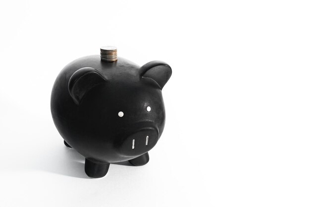 Photo black piggy bank with pillar of cents on a white background