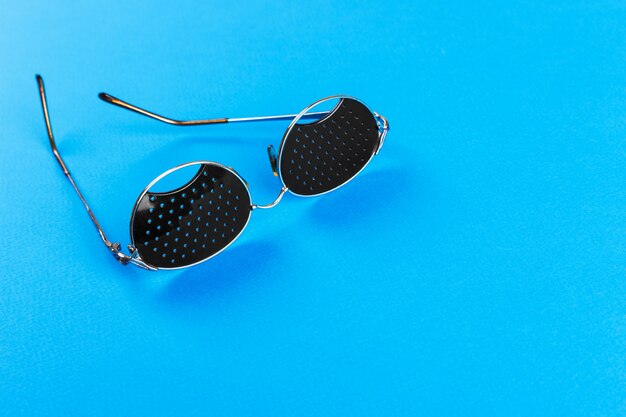 Black pinhole glasses on blue