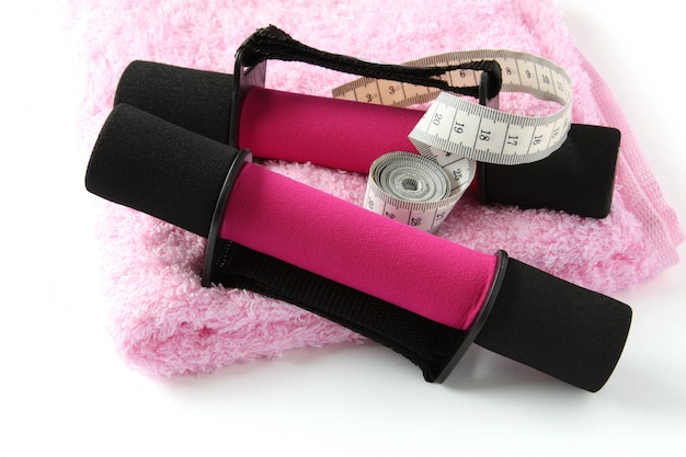 Black-pink soft dumbbell with handle strap and measuring tape on towel over white