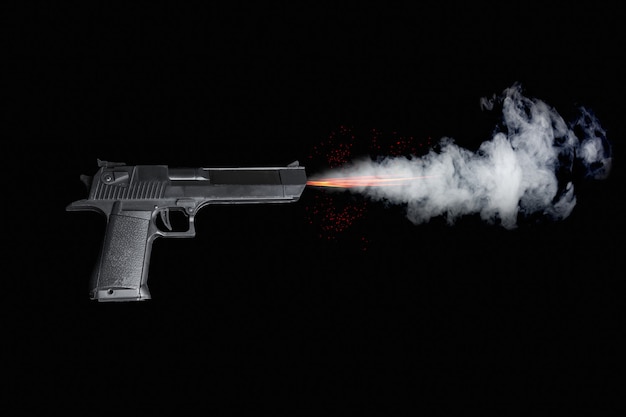 Black pistol shooting with fire, sparks and smoke on dark background.