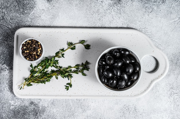 Photo black pitted olives on a white chopping board. gray background. top view. space for text
