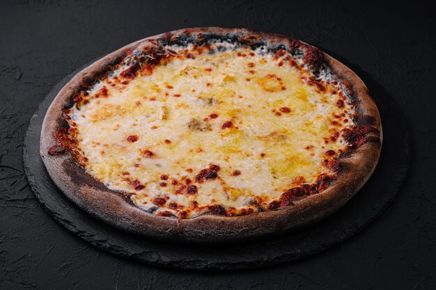 black pizza with cheese on stone