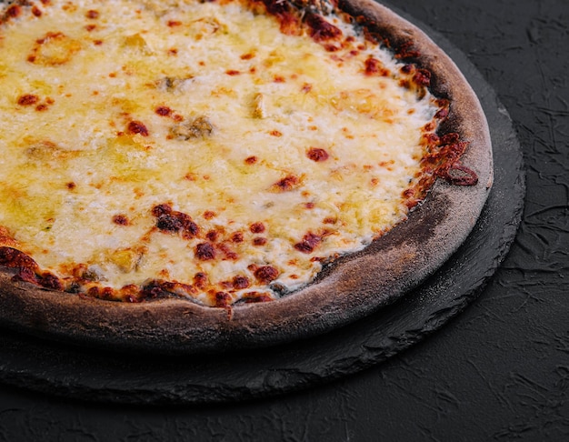 black pizza with cheese on stone