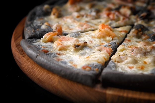 Photo black pizza on a wooden board