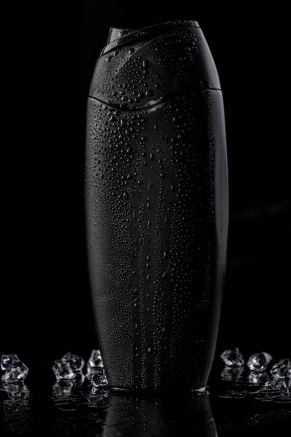 Black plastic bottle for shampoo with ice cubes