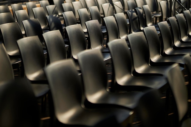 Black plastic chairs stand in rows black chairs with backs