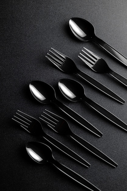 Black plastic cutlery on black floor