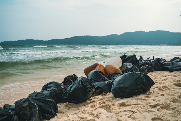 Black plastic garbage bags full of trash on the beach. Garbage collection, cleaning of the nature, garbage collection on the beach.