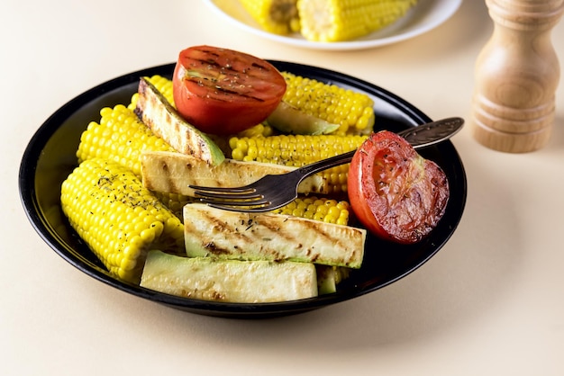 Piatto nero di zucchine vegetali grigliate corntomato dieta gustosa e sana cibo sfondo giallo