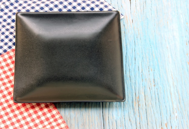 Black plate on tablecloth on wood table background