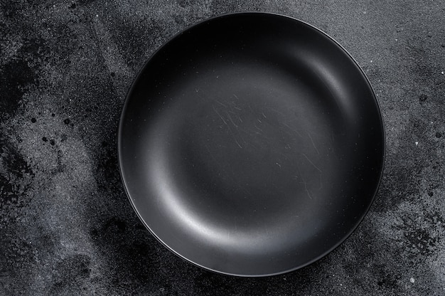 Black plate on textured black background.  Top view. Copy space