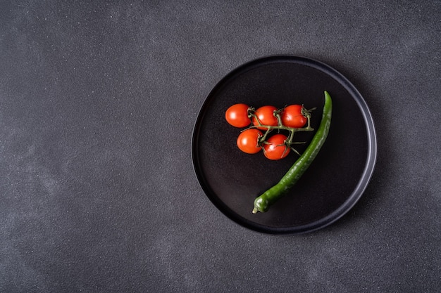 Black plate with cherry tomatoes and pepper