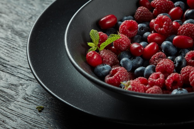 어두운 표면에 신선한 건강한 딸기와 민트와 블랙 플레이트