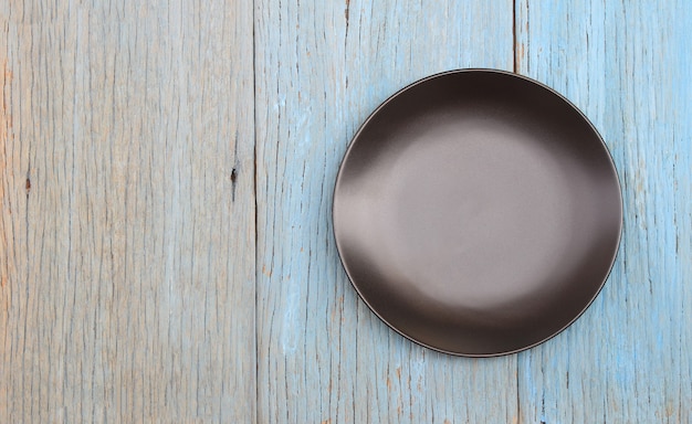 Black plate on wood table background