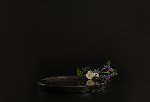 Black podium on the black background with flowersPodium for product cosmetic presentationMock up