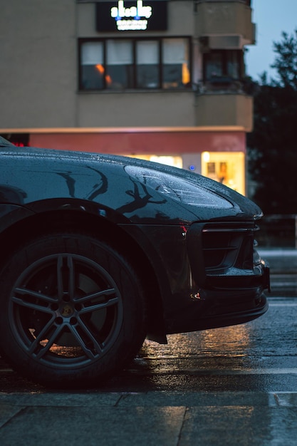 a black porsche is parked in the rain