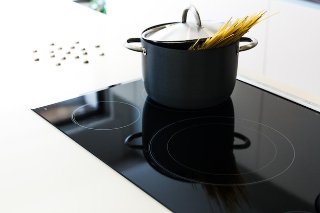 Foto possa nera con coperchio per la cottura di spaghetti in cucina moderna su cucinetto a induzione