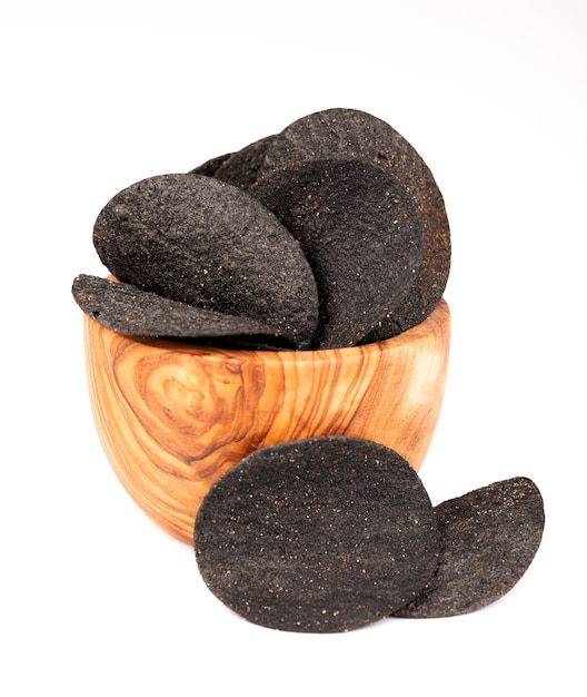 Foto patatine fritte nere in ciotola di oliva, isolate su fondo bianco. patatine nere con carbone attivo e peperoncino.