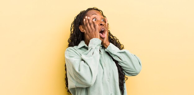 black pretty woman feeling happy excited and surprised looking to the side with both hands on face