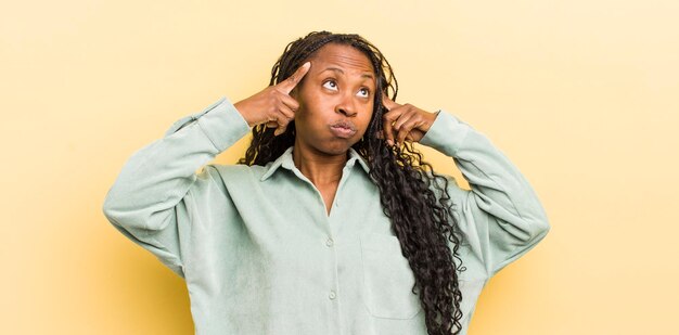 Black pretty woman looking concentrated and thinking hard on an idea imagining a solution to a challenge or problem