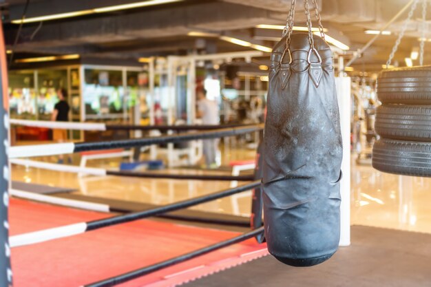 Black punching bag hanging in Abstract blur of defocused boxing gym interior and fitness h